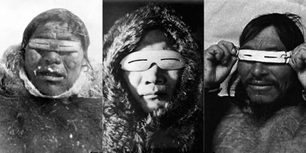 Inuit people wearing their ivory-derived snow goggles.